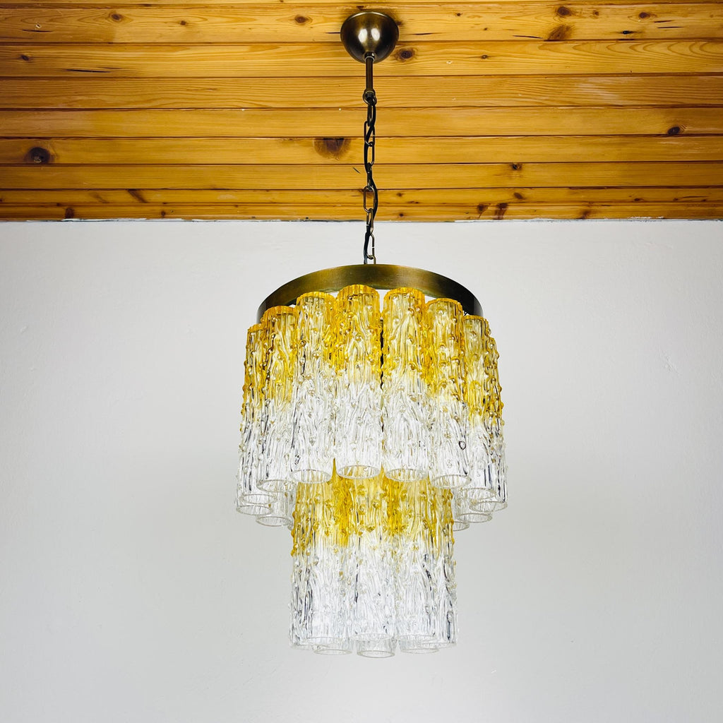Chandelier with yellow and clear glass design hanging from a wooden ceiling.