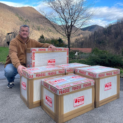 Man posing with large cardboard boxes labeled 'Fragile' in a mountainous area.