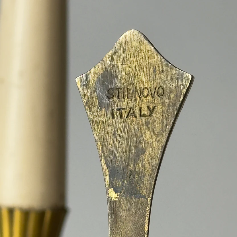 Close-up of a brass tool with 'STILNOVO ITALY' engraving on a gray background